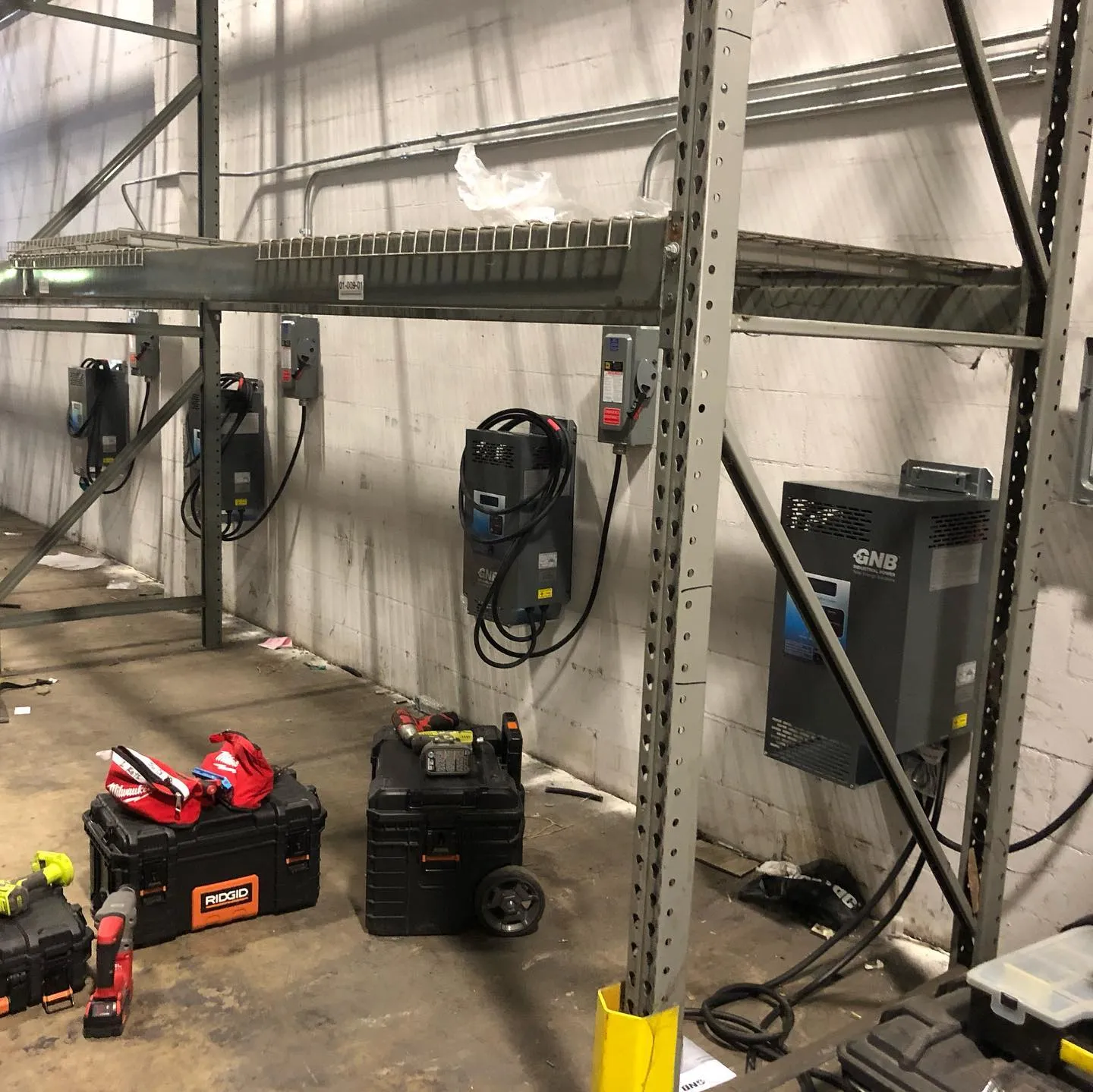 Three electric vehicle chargers mounted along a commercial garage wall