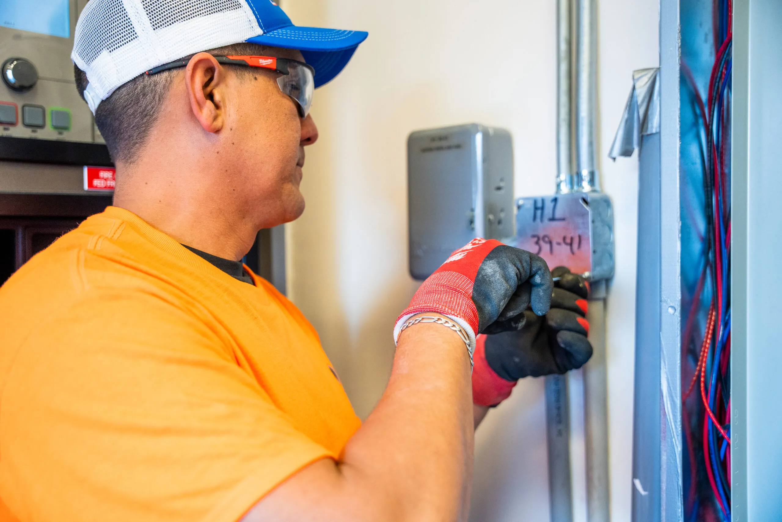 A Premium Electric electrician in safety glasses and work gloves checking a wall-mounted meter