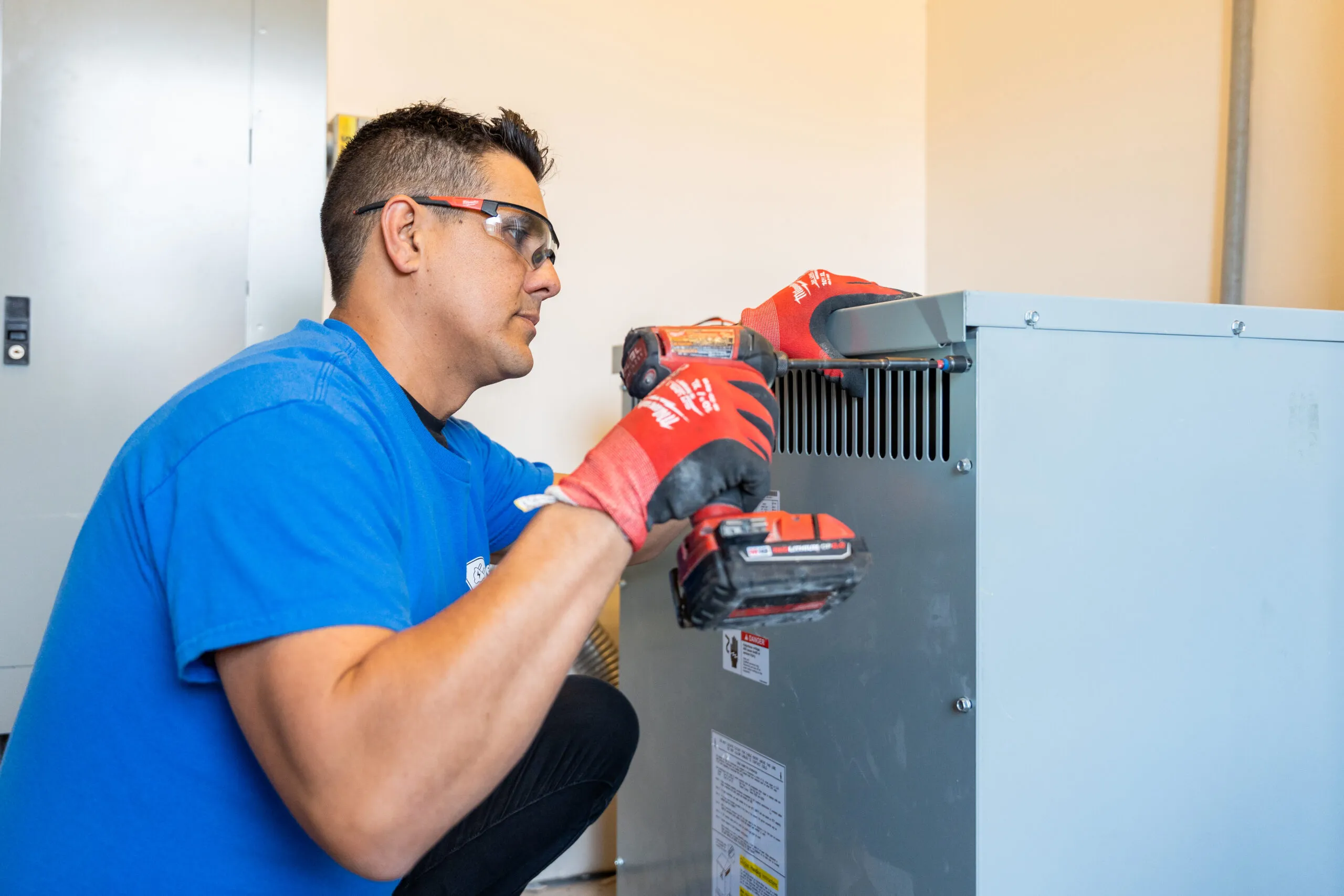 A Premium Electric electrician fastening the cover on a commercial transformer with an impact driver